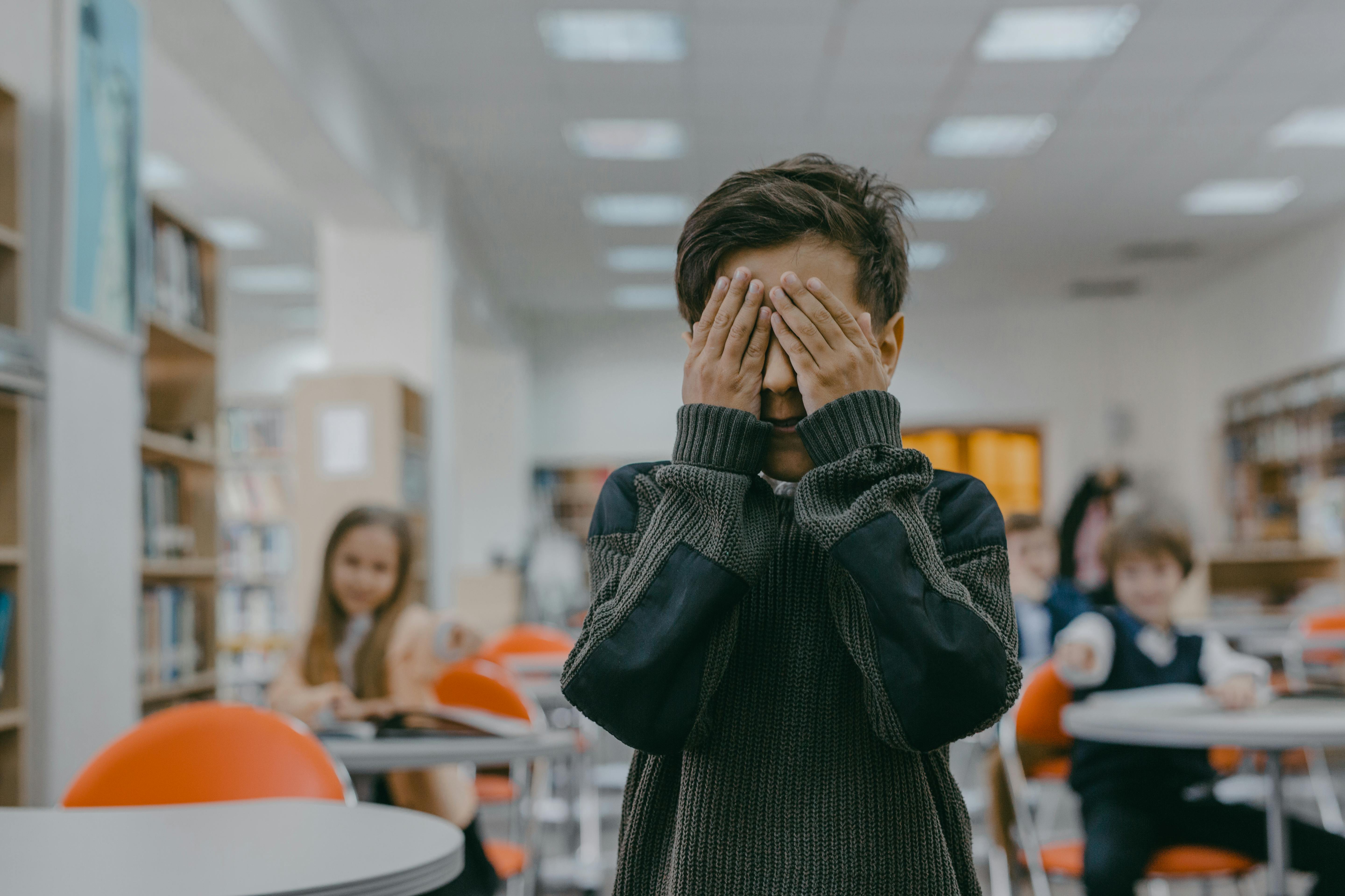 Image of Boy covering his face and stressed out in a clasroom